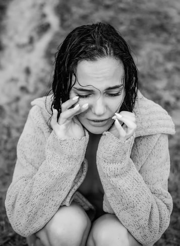 Woman in a crouched, closed position looking distraught and upset because of addiction symptoms. Treatment for addiction through wellness counseling and addiction therapy is available in Ewing, NJ