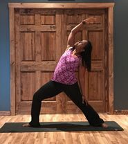 Woman doing yoga in front of a wooden door in Ewing, NJ. Mindfulness focused yoga practice with trained therapists who center intersectionality, diversity and holistic approaches to treatment.