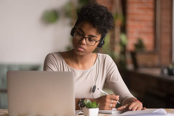 Woman looking serious, staring down at computer with headphones and working on documents. Depression treatment and anxiety therapy in Ewing, NJ can help you feel better at Mindful and Multicultural Counseling. You can also get help with online therapy in New Jersey.